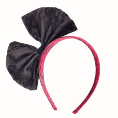 Pair of 80s-style lace headbands in pink and green, each featuring a black bow, displayed on a white background