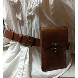 Medieval-style belt bag in brown with bronze-gold rivet details, worn on a mannequin dressed in a white medieval shirt, showcasing how the bag is worn with a belt