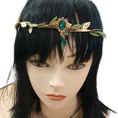 Mannequin head with a black wig wearing an Elven Leaf Crown featuring a brown base, green and gold woven leaves, a green gem in a gold casing with swirly details at the front, and another green gem hanging below