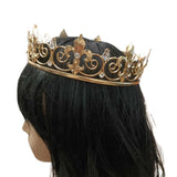Side view of a mannequin head with a black wig wearing a gold crown featuring fleur-de-lis shapes and clear gems, showcasing the crown's profile