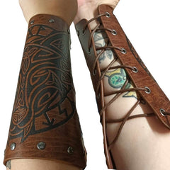 Pair of Viking-style wrist braces worn on a wrist, featuring a black embossed wolf design on the front, dull silver rivet details, and a leather-look brown finish. The back view shows silver eyelets with brown cord lacing, against a white background