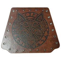 Pair of Viking-style wrist braces worn on a wrist, featuring a black embossed wolf design on the front, dull silver rivet details, and a leather-look brown finish. The back view shows silver eyelets with brown cord lacing, against a white background