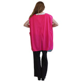 A woman viewed from the back wearing a bright pink sleeveless poncho-style cover-up over a white top and black pants, against a plain white background.