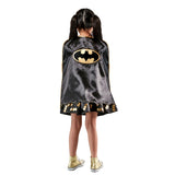 A child shown from the back wearing a black Batman cape with gold trim and a large gold Batman logo on the back, photographed against a plain white background.