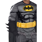 A child wearing a gray and black Batman costume with a yellow utility belt and yellow Batman logo on the chest, shown against a plain white background.