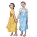Two young girls modeling princess costumes, one in a yellow gown with a brown bodice and the other in a light blue gown with a white bodice, standing against a white background.