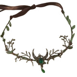 Decorative headpiece with green gemstones and brown ribbon on a white background