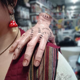 Second image showing the fake hand Halloween prop draped over the front of an adult's shoulder, highlighting the realistic stitched detailing and eerie positioning.