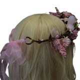 Floral headpiece with pink ribbons on a blonde wig against a white background