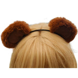 Brown fuzzy ears on a headband worn by a person with blonde hair against a white background