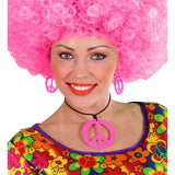Person wearing a bright pink afro wig and colorful floral top with peace sign accessories on a white background
