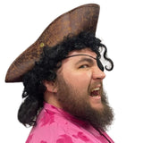 Person wearing a pirate hat and eyepatch with a pink shirt on a white background