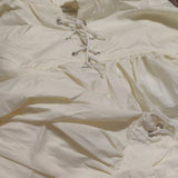 Close-up of a beige shirt with lace-up front design.