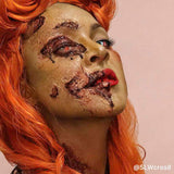 Person with zombie makeup and orange hair on a plain background
