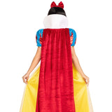 A child shown from the back wearing a Snow White costume, featuring a red cape, yellow skirt, blue sleeves, and a red bow in the hair, against a plain white background.
