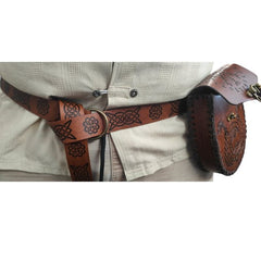 Brown leather bag with embossed designs and a strap on a white background