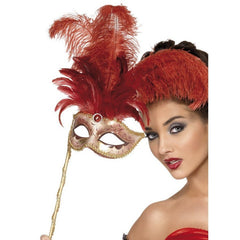 person holding ornate masquarade mask in gold and red with large red feathers